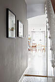 Framed artwork in light grey hallway with view to sunlit kitchen in London home  UK