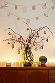 Christmas baubles on twig arrangement with lighting on sideboard in London home  UK
