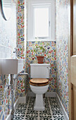 Floral patterned wallpaper in small bathroom of London home  UK