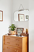 Vintage mirror above wooden chest of drawers in London bedroom  UK