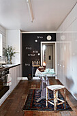 White cupboards and wooden floor with Norse vintage rugs and black feature wall in Rochester galley kitchen  Kent  UK