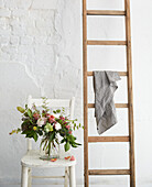 Cut flowers and ladder in whitewashed London studio  UK