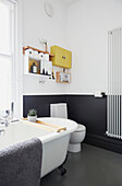Freistehendes Rolltop und Toilette in einem schwarz gestrichenen Badezimmer in einer modernisierten Wohnung in Preston, Lancashire, England UK