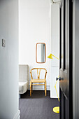 Yellow floor lamp with chair below mirror in spare room of modernised Preston home  Lancashire  England  UK
