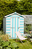 Bright blue striped shed and deckchair in garden  East Riding of Yorkshire  England  UK