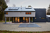 Modernes neues Gebäude mit Sonnenkollektoren und überdachter Terrasse in einem Waldgebiet in Devon UK