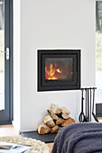 Lit fire and logs with hearth set in Devon new build  UK