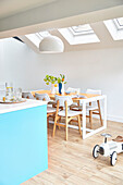 Table and chairs below skylight windows with toy car  in modernised kitchen extension  London  UK