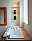 Bath with stone surround and glass shelving set in alcove