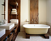 Modern bathroom with roll top bath and dark wood fittings