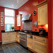 Küche mit leuchtend rot gestrichenen Wänden und Küchenschränken aus massiver Buche