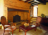 Exposed brick inglenook fireplace in traditional French style living room with upholstered armchairs
