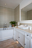 Neutrally decorated bathroom in white and beige with built in cupboards and vanity basin