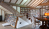 Books and CDs on shelving under beamed ceiling in watermill conversion