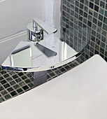 Moderne Armatur mit grauen Mosaikfliesen am Waschbecken in der Nasszelle einer umgebauten Wassermühle