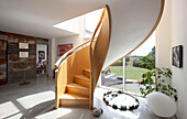 Sunlit spiral staircase in spacious entrance hall of Essex home UK