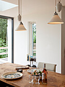 Pendelleuchten über einem Esstisch mit Tellern für das Mittagessen in einem Haus in Essex, UK