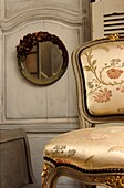 Still life of French upholstered fauteuil and decorative mirror