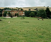 Garden view of Georgian country house in Devon with horse riders