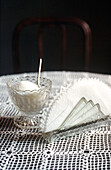 Still life of glass sugar bowl and napkins on lace tablecloth 