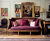 Purple upholstered vintage sofa with cushions in a wood paneled living room