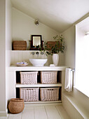 Built in unit with countertop wash basin and storage baskets in attic bathroom painted in neutral tones