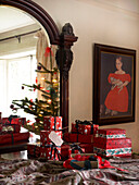 Reflection of decorated christmas tree in mirror with gift wrapped presents in foreground