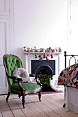 Bedroom detail with green velvet upholstered balloon back chair beside festive decorated fireplace