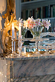 Detail of marble fireplace in living room decorated with vintage glassware and fairy lights