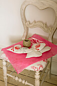 Weiß gestrichener Stuhl mit rosa Seidenpapierschnur und hübschen Lavendelherzen aus Leinen als Geschenk