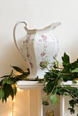 Berried ivy garland draped across the mantlepiece with large green ewer and fairy lights