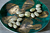 Gold and green lustre dish decorated with string instruments and filled with sugared almonds