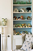 Wohnzimmer mit einem Regal voller Geschirr, Vasen und kleinen Figürchen