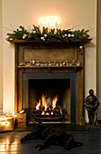 Lit fire and candles with garland on wooden fireplace