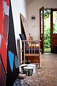Tins of paint and canvas with chair in Suffolk artist's studio with open door