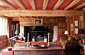 Beamed sitting room with panelling around inglenook to conceal television and audio equipment