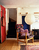 Armchair and panelled door with latch in whitewashed cottage interior