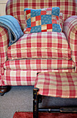 Checked armchair and footstool with patchwork cushion