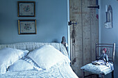 Kissen und Kunstwerke in einem hellblauen Schlafzimmer im Landhausstil