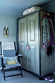 Kleiderschrank und Klappstuhl in einem Schlafzimmer auf dem Land mit Schals