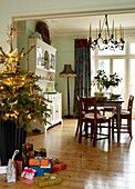 Weihnachtsbaum und Geschenke im offen gestalteten Esszimmer mit Kronleuchter und weihnachtlich gedecktem Tisch