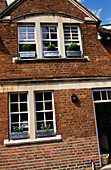 Brickwork facade of Oxfordshire house window boxes on narrow sash windows