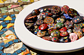 A dish of vintage decorated buttons on a mosaic table top 