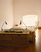 Low bed and chest of drawers with lamps correspond with windows set low in the walls 