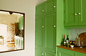 Green painted kitchen units and vintage pub mirror fixed to wall