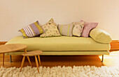 Daybed with cushions and smoothed wooden nest of tables with sheepskin rug