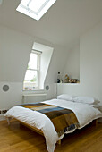 Double bed with blanket in white bedroom with dormer window