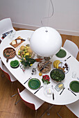 Overhead view of white pendant light and dining table set with green crockery 