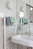 White bathroom with heated radiator and shaving mirror above wash basin