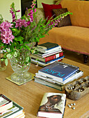 Vase of flowers and hardback books on wooden coffee table